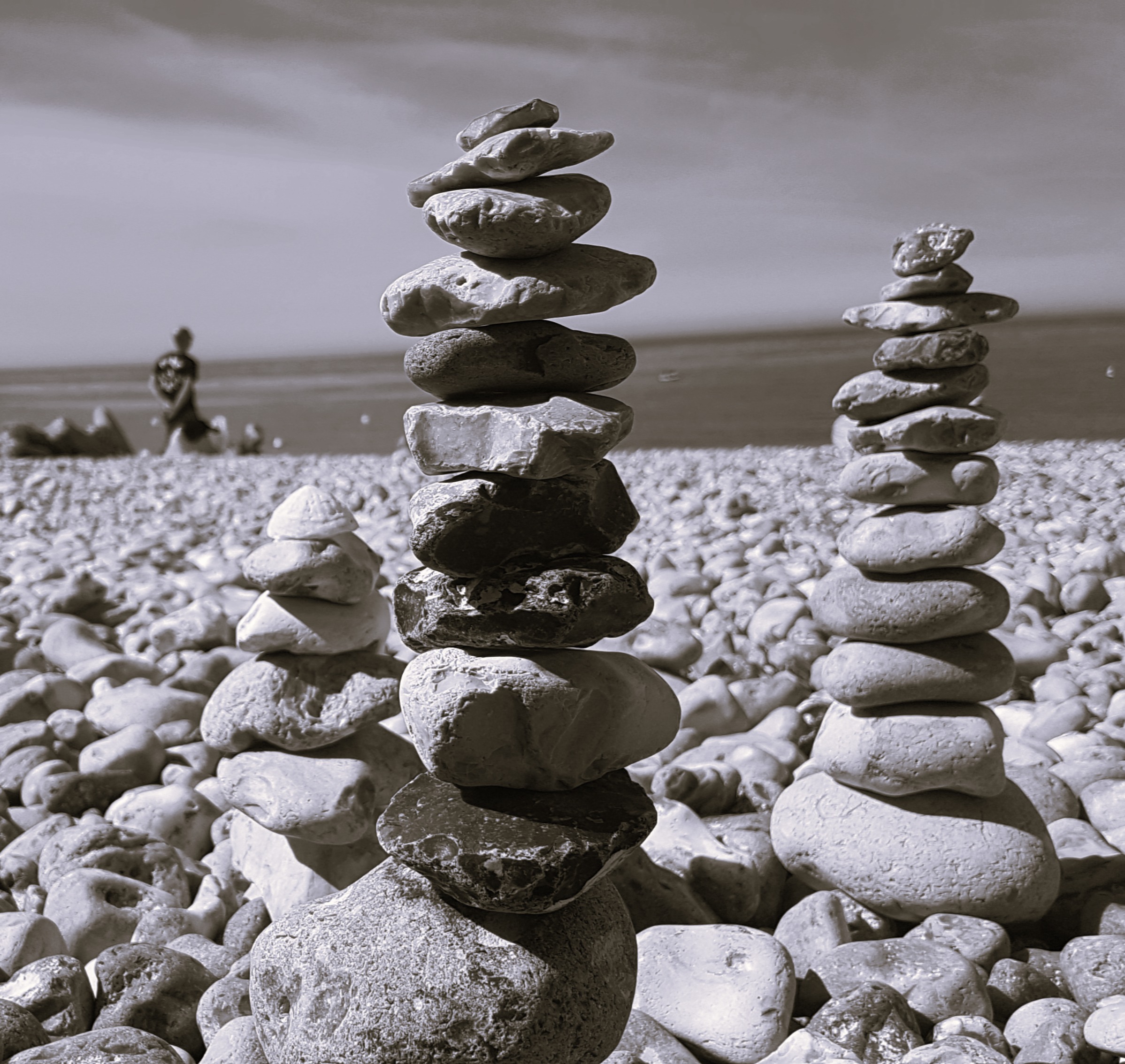 viele kleine übereinander gestapelte Steine, die kleine Türme am Strand bilden
